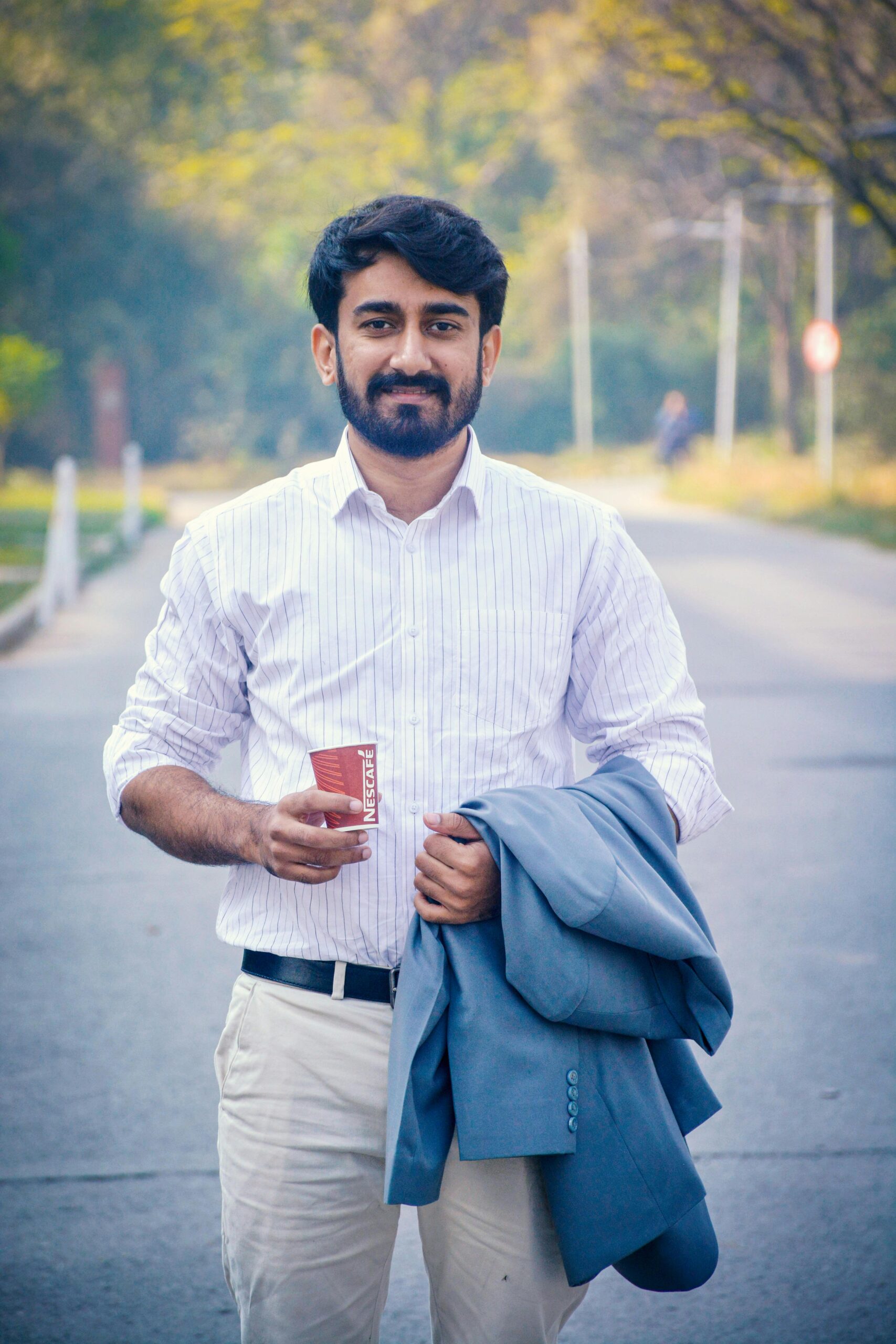 Confident man in white shirt with coffee cup outdoors in Islamabad, Pakistan.